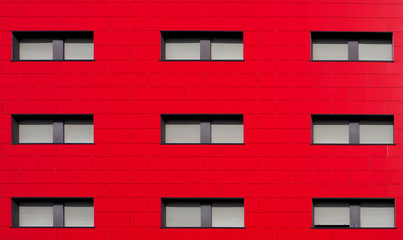 Bright red facade of a modern residential building with gray shutters