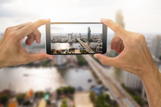 Man's hands holding smartphone taking photo of Bangkok city,Thailand