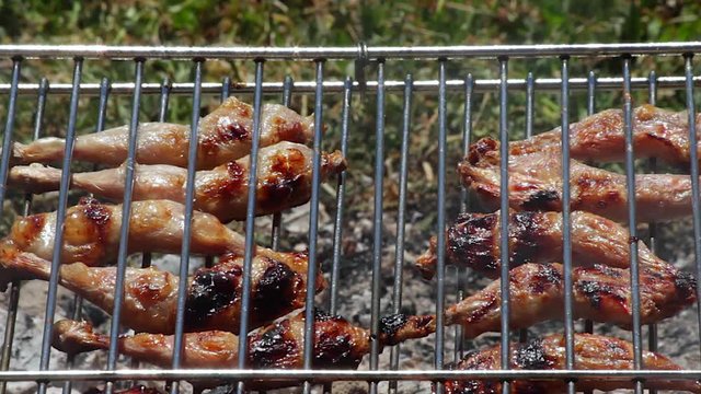 Detalle de Muslos de Codorniz as&aacute;ndose en la brasa de la parrilla 