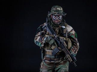 Bearded Special forces United States in Camouflage Uniforms studio shot half length black background. Holding weapons, wearing jungle hat, Shemagh scarf, he is ready to kill. Backlit