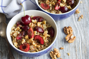 Healthy delicious vegan breakfast. Quinoa with fresh cherries, walnuts and honey on the blue background
