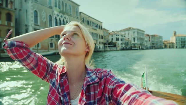 Woman is photographing herself against the background of buildings on a canal in Venice. Tourism in Italy