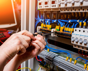 The man is repairing the switchboard voltage with automatic switches.