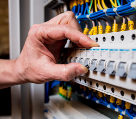 The man is repairing the switchboard voltage with automatic switches.