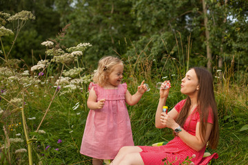 Young mother with little daughter playing with soap bubbles
