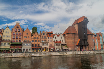 Fototapeta na wymiar GDANSK, POLAND - SEPTEMBER 2, 2016: Riverside houses by Motlawa river in Gdansk, Poland. Medieval crane in the background.
