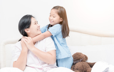 cute asian girl smile and hugging mother on bed in morning