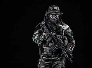 Bearded Special forces United States in Camouflage Uniforms studio shot half length black background. Holding weapons, wearing jungle hat, Shemagh scarf, he is ready to kill. Backlit