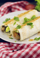Lavash rolls with meat, vegetables and cheese served with green lettuce salad on rustic wooden table. Healthy breakfast concept. Greek traditional food - Gyro.