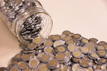 glass jar with many mexican pesos coins