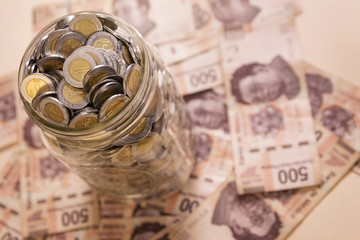 mexican pesos banknotes and coins in glass jar