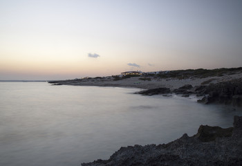 Sunset light by the sea in Formentera with houses turning on the light