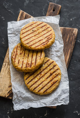 Grilled vegetarian chickpea and cauliflower burger cutlets on wooden cutting Board on a dark background. Top view