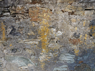 Alte Feldsteinmauer mit kaputtem Putz und Flechten