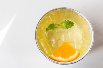 Top view of water with ice cubes, orange sliced and mint leaves.