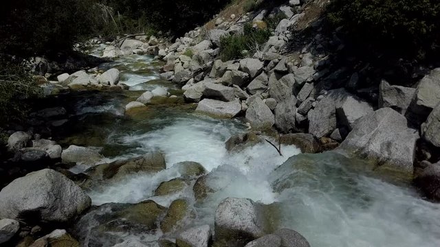 Aerial cool refreshing mountain river stream. Beautiful clear water mountain stream, springtime snow melt. Rocks and fallen timber logs in waterfalls. Forest nature in natural environment. Little Cott