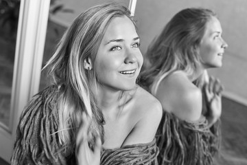 Fototapeta premium Positive human facial expressions and emotions. Black & white portrait of surprised astonished lady sitting in front of mirror looking happily sideways in full disbelief with wide beautiful smile.