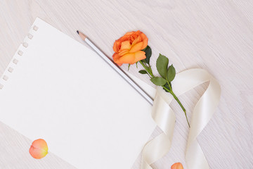 Creative mock up layout made of roses  with copy space on table homemade flat lay. Empty sheet of paper. Mockup with a card and orang rose