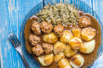 Homemade fried meatballs served with potatoes and cabbage.