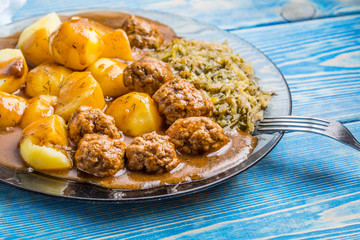 Homemade fried meatballs served with potatoes and cabbage.