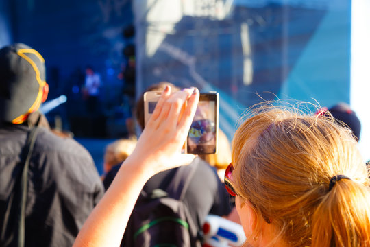 Close Up Of Recording Video With Smartphone During A Concert. View From Behind, Blur Effect