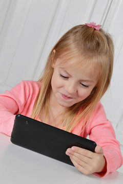 fillette blonde de 6 ans jouant sur une tablette