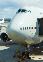 Close-up of very large wide-body airplane being prepared for towing, with tow-truck connected.