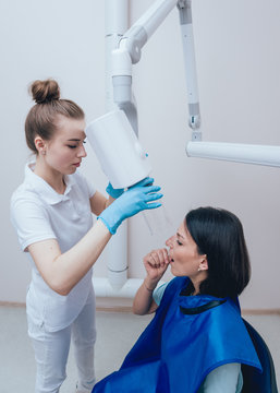 Dentist make x-ray image for young woman in dental clinic. Aiming dental radiography.