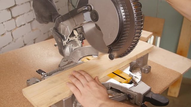 Electric circular saw cutting piece of wood in sawmill