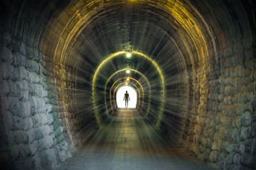 Light at the end of ancient narrow tunnel with man silhouette standing. Life after death, problem...