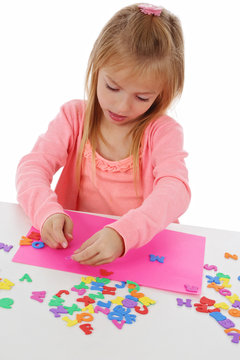 fillette 6 ans jouant avec lettres &agrave; coller 