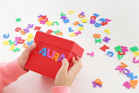 fillette 6 ans jouant avec lettres &agrave; coller 