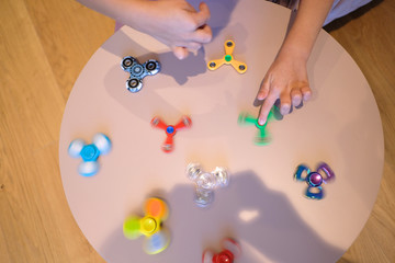 Hands of a child playing at a table with spinners