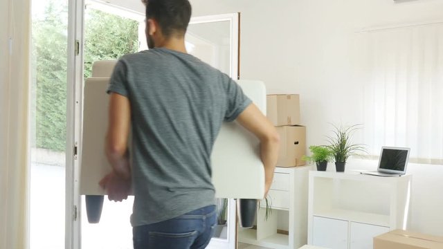 happy young couple student roommate carrying a sofa and moving boxes during their move into new home flat apartment