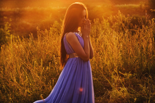 Beautiful girl at sunset praying