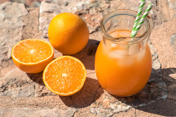 Fresh orange juice and oranges isolated on a stone surface.