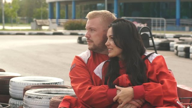 young loving couple sitting on the go-kart track and talks