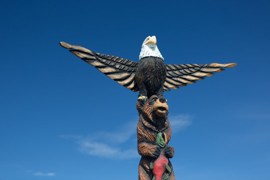 A carved wooden alaskan totem pole against blue sky