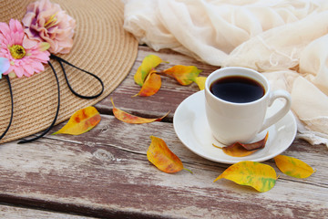image of coffee cup over wooden table and autumn leaves