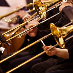 Trombones in the hands of musicians in the orchestra closeup