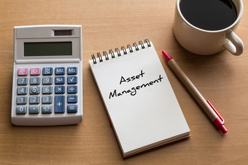 Asset Management, business conceptual - handwriting on notepad with cup of coffee and calculator