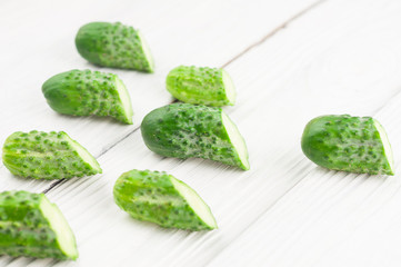 Lot of half of green fresh cucumbers on rustic white wooden planks