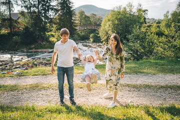 young family plaing with her daughter in mountains