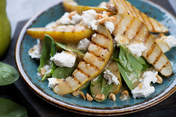 Close-up of salad with fresh spinach, grilled pears and cheese, selective focus, horizontal shot
