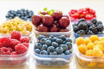 Collage of different fruits and berries isolated on white. Blueberries, cherries, blackberries, grapes, strawberries, currants. Collection of fruits and berries in a bowl. Top view