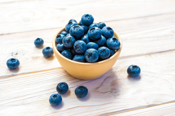 Blueberries in a wooden bowl. Top view. Ripe and tasty blueberries on a wooden background