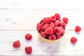 Raspberries bowl on rustic wood background, top view with copy space. Organic berries on wooden table