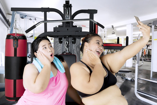 Fat women with smartphone in the fitness center