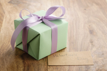 green gift box with purple bow wood background with valentines day greeting card