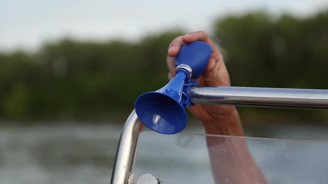 A man press on the manual klaxon mounted on the boat